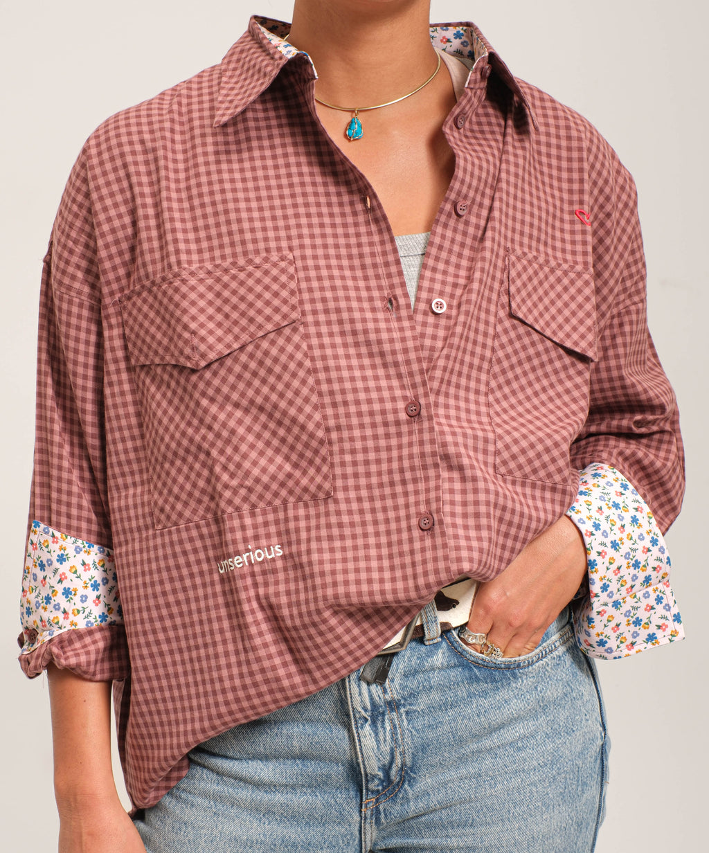Person wearing a plaid shirt with rolled-up sleeves and jeans on a plain background
